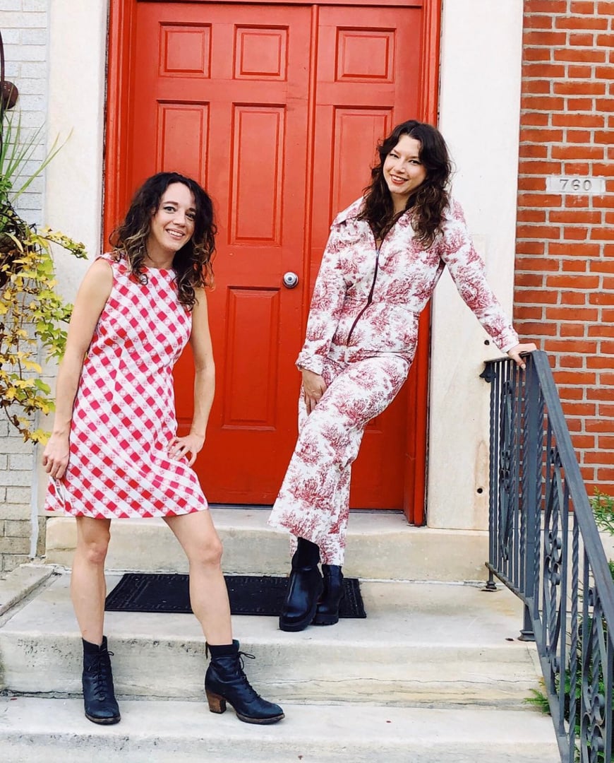 two people standing on steps in front of a red door